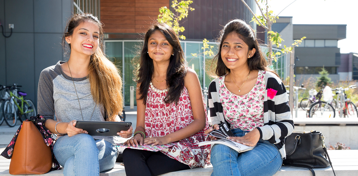 picture of Centennial College International Education students sitting outside Progress Campus library smiling